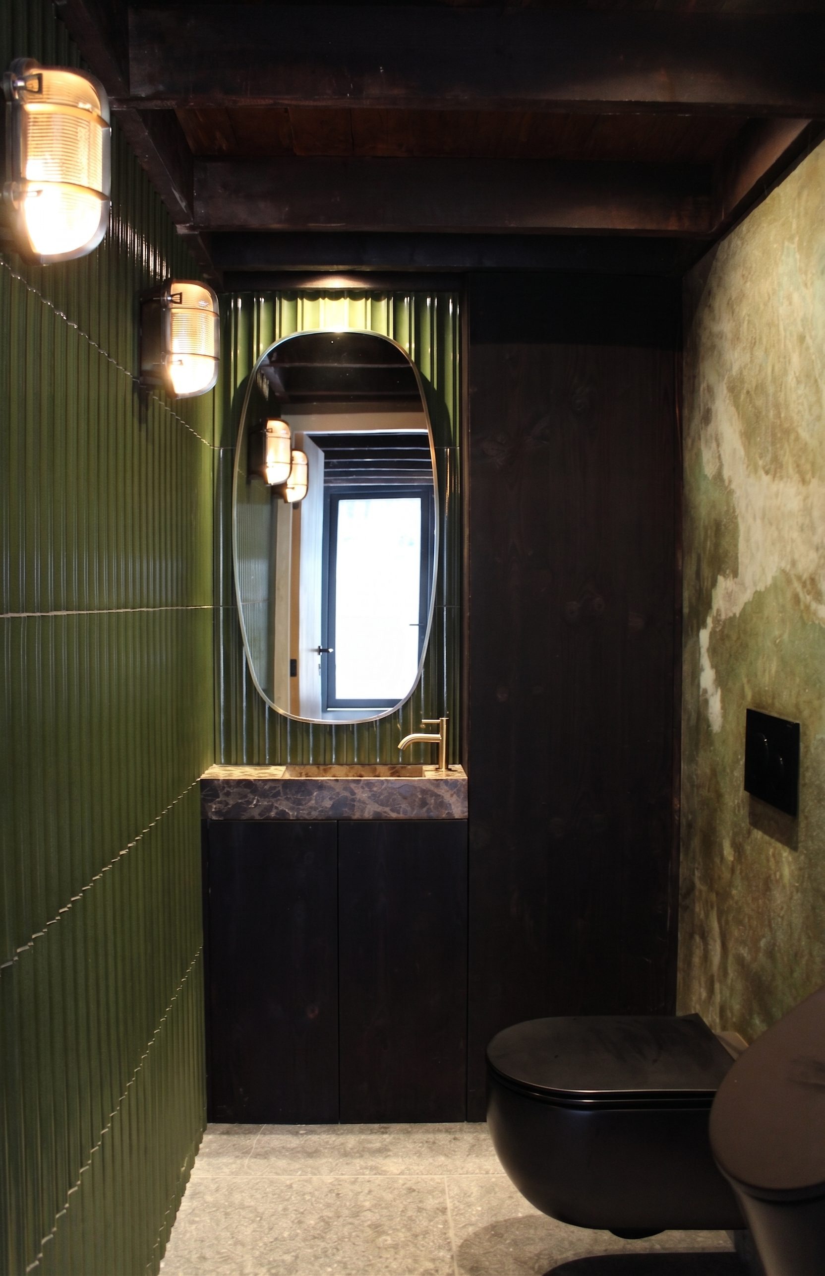 Toilet met gepatineerde en lasergesneden messing platen, arduin en Yakisugi meubel onder het originele balkenplafond