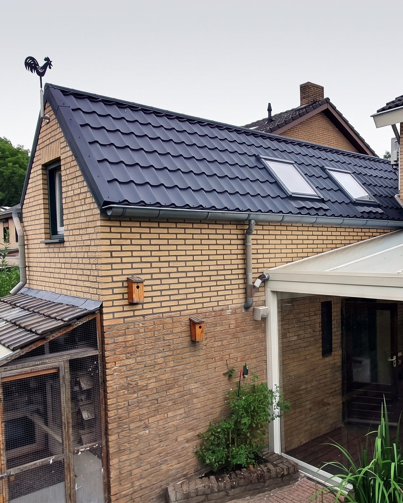 De achterzijde van de opgetopte garage vanuit de tuin: nieuwe kopgevel in metselwerk met twee dakramen in het dakvlak